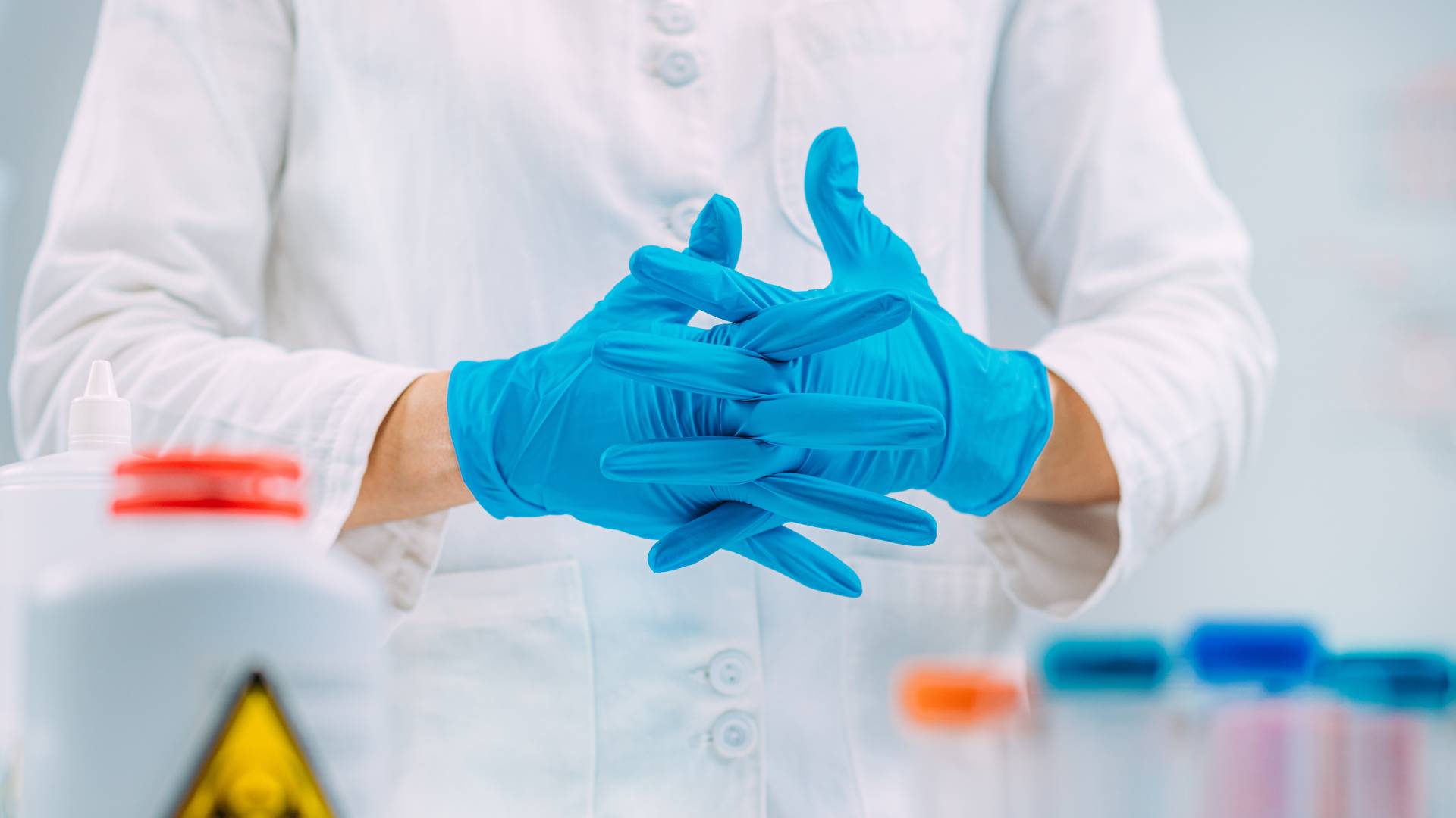 Persona in laboratorio chimico con camice e guanti in nitrile