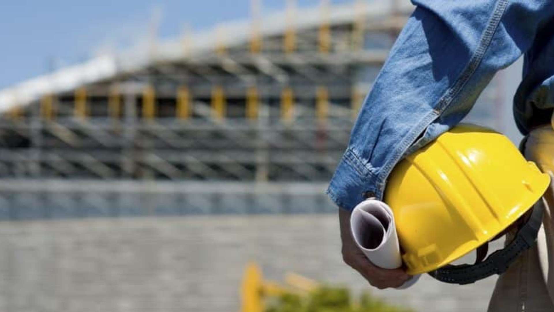 Uomo con elmetto in mano davanti un cantiere 