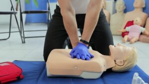 Persona che effettua una rova di massaggio cardiaco su manichino a mezzo busto