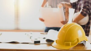 Personale con foglio in mano, elmetto giallo appoggiato sul tavolo