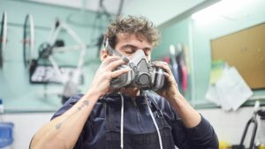 Uomo che indossa una maschera per la protezione delle vie aeree, con due filtri laterali.