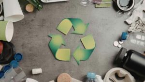 Simbolo del ricliclo verde con qualche rifiuto attorno