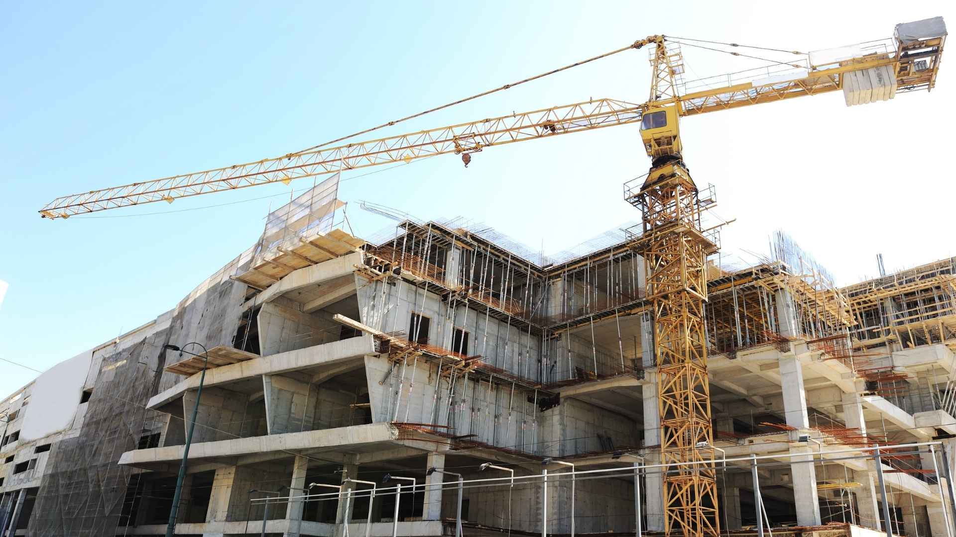Gru da cantiere con palazzo in costruzioni circondato da ponteggi